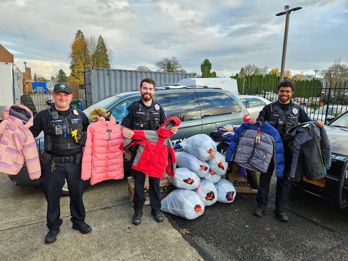 Forest Grove police officers stand with coats collected for local families through the GG's House partnership